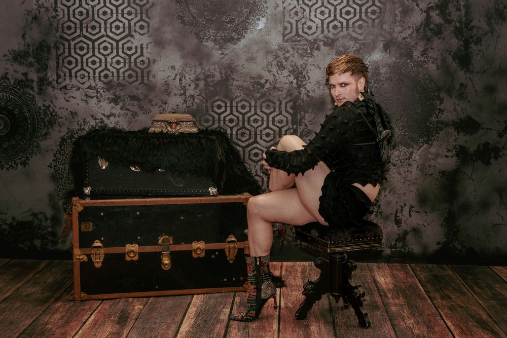 Seated pose on a black chair with a confident expression and vintage styling