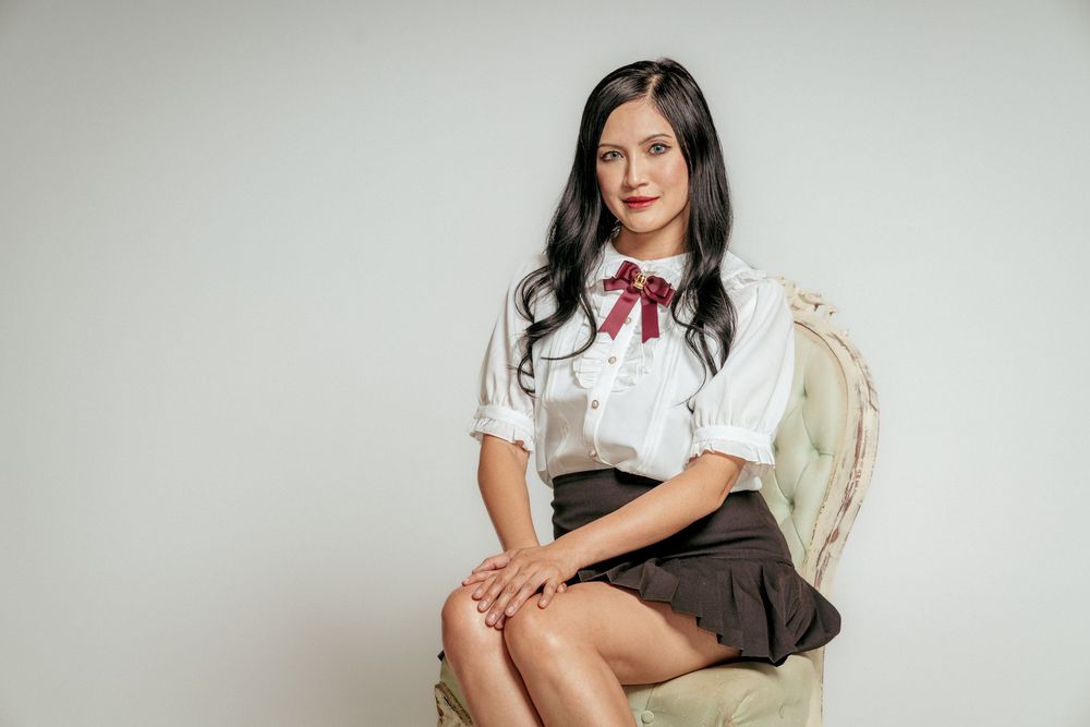 Portrait of a woman sitting confidently in a gray chair against a white background