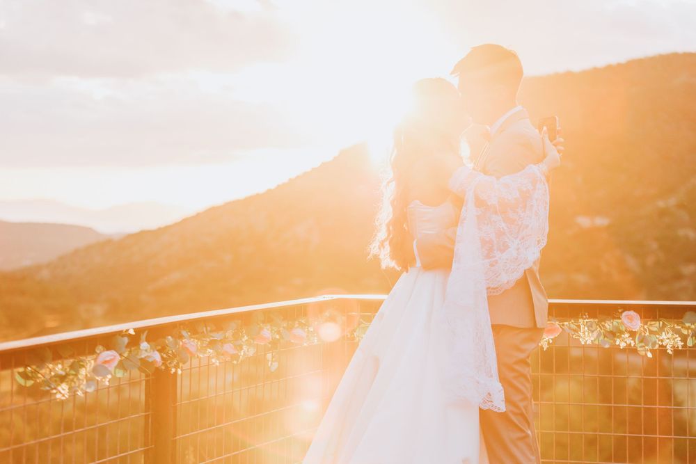 Golden sunlight illuminates a scenic mountain landscape with string lights and white fabric decorations at sunset.