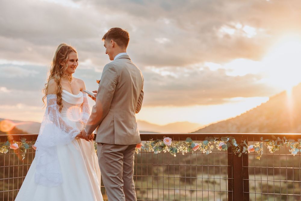 A couple shares an intimate moment during sunset at their outdoor wedding ceremony with golden light streaming behind them.
