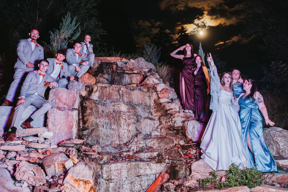 Wedding couple poses in front of a rocky cave backdrop with dramatic lighting and smoke effects.