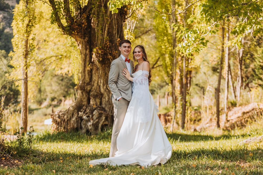 A romantic outdoor photo session in a sunlit forest with golden autumn light filtering through the trees.