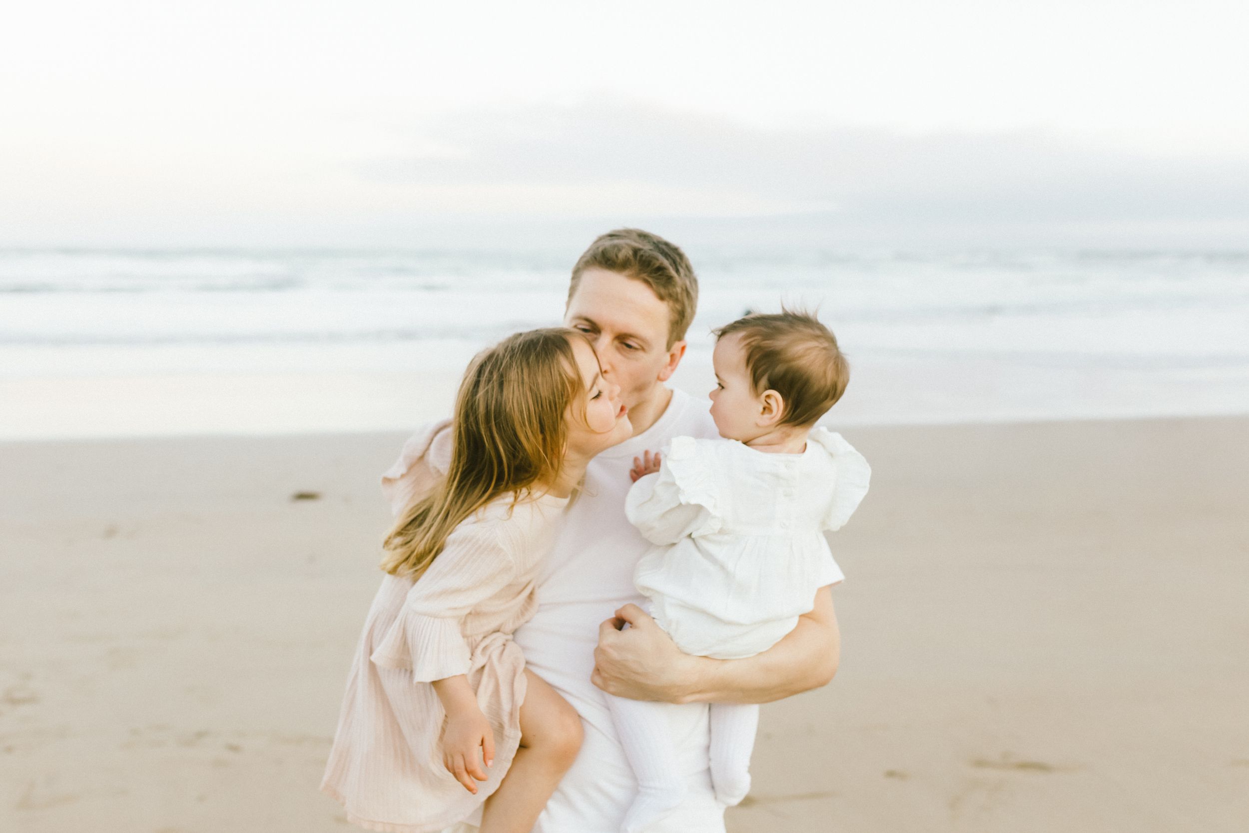 A family shares a tender moment together on a peaceful beach at sunset.