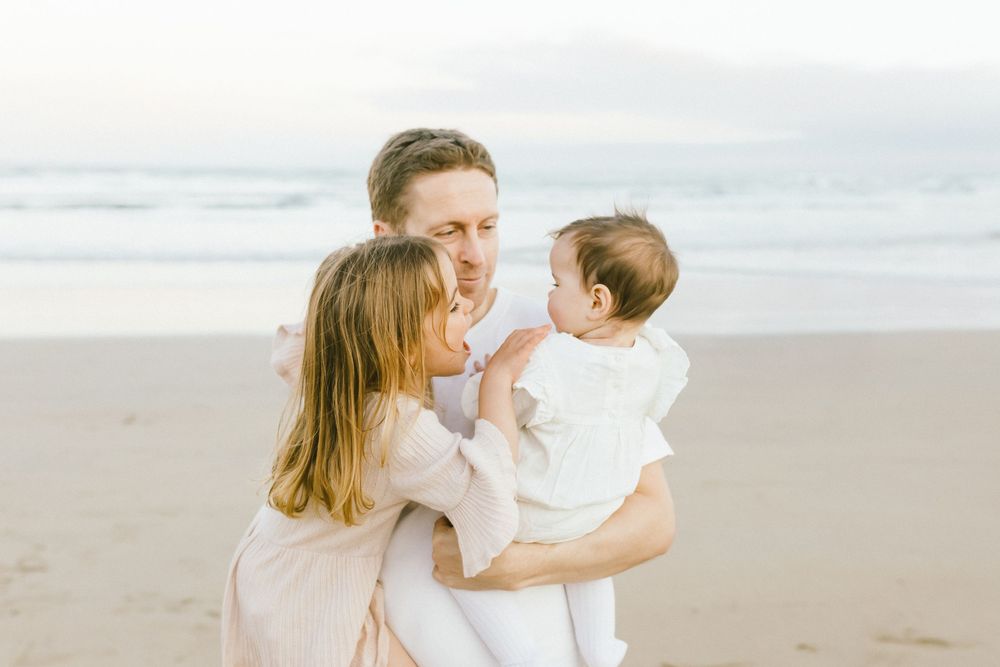 A parent and child share tender moments together while walking along a misty beach at sunset.