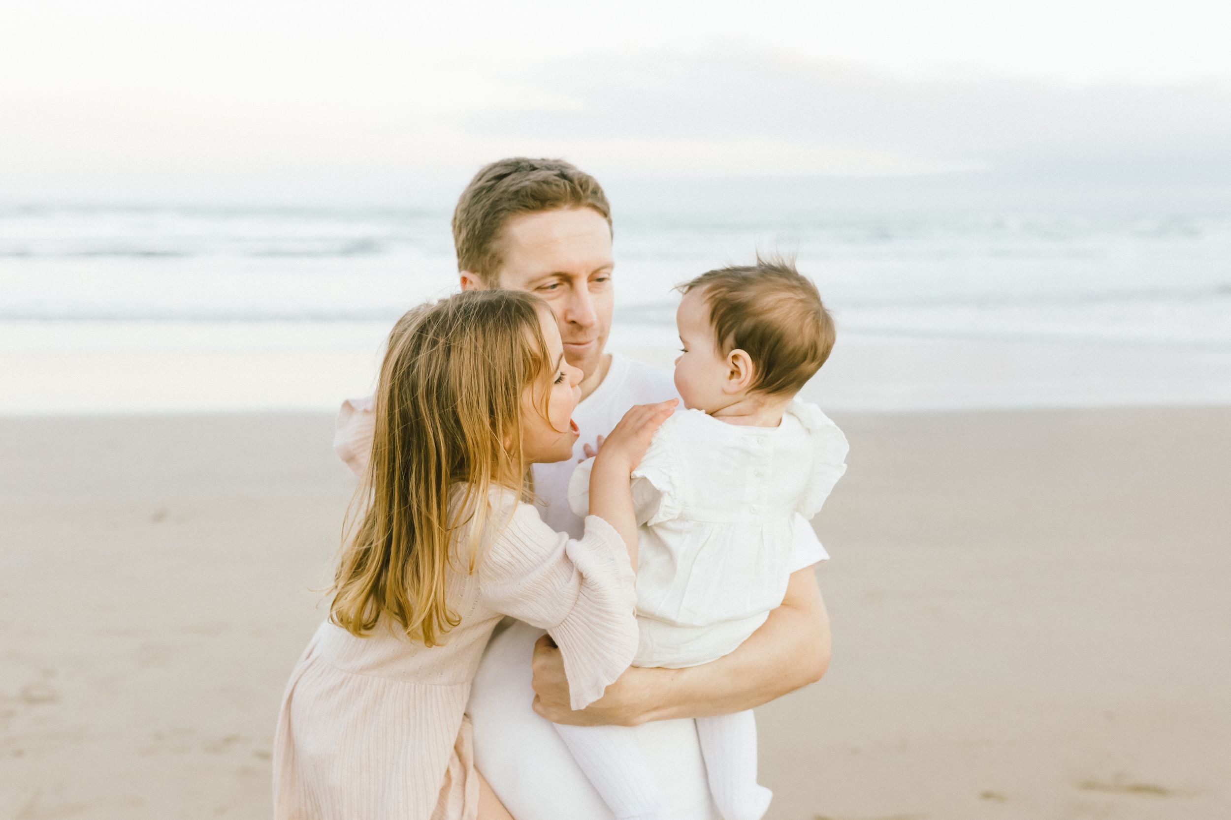 A parent and child share tender moments together while walking along a misty beach at sunset.