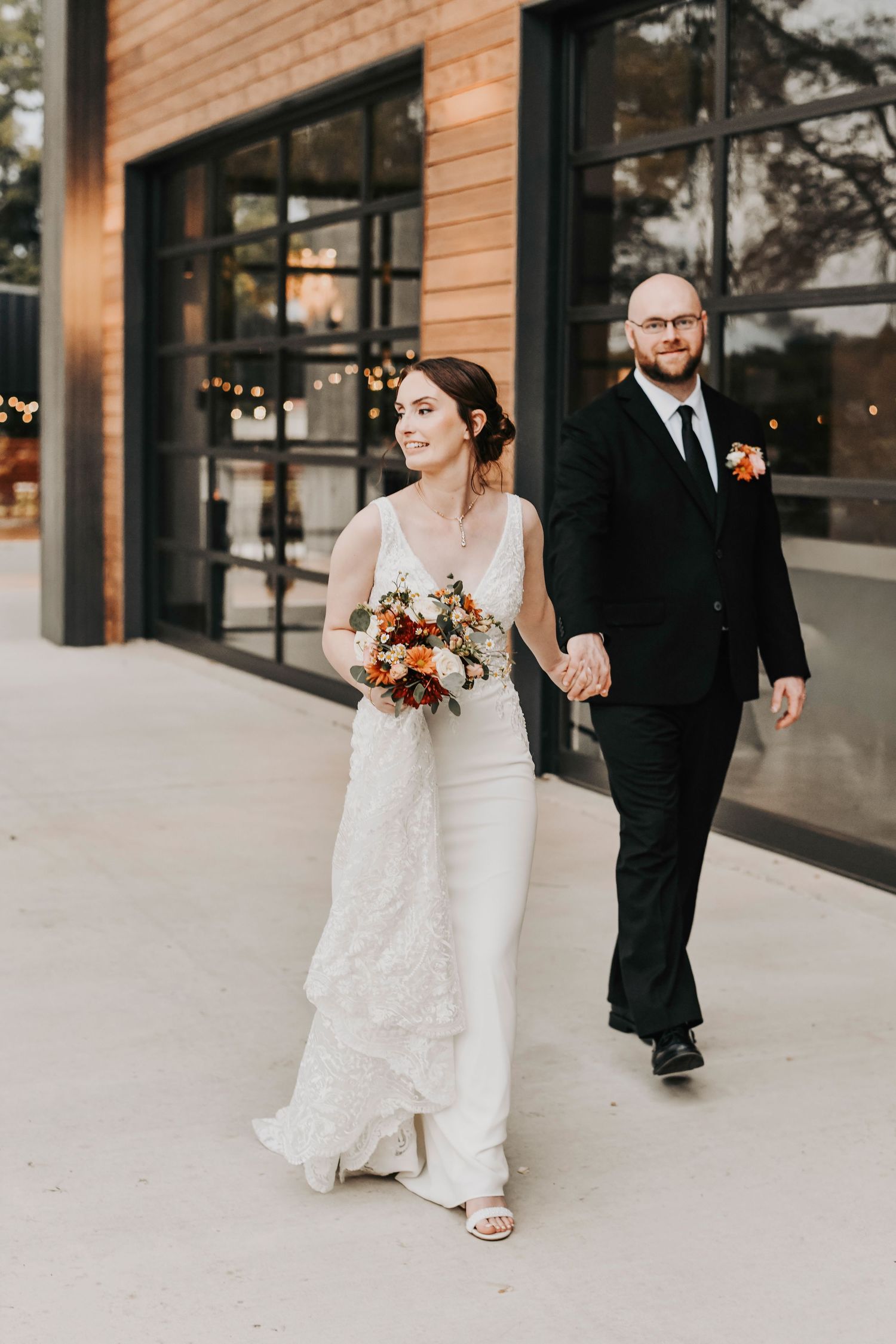 a candid photo of a bride and groom holding hands and walking in the sunset at their weatherford wedding venue