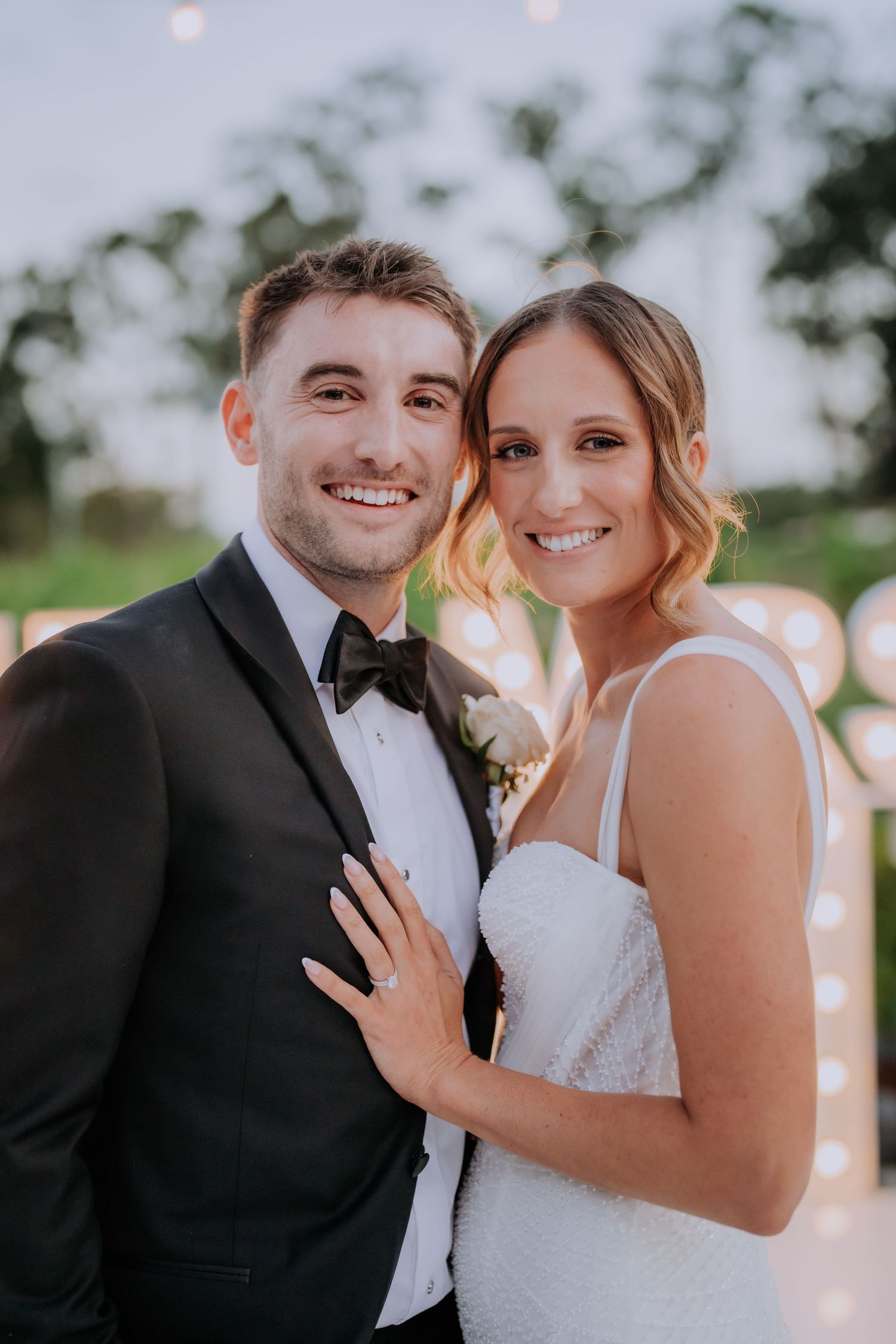 Romantic outdoor wedding portrait at sunset with soft lighting and natural background.