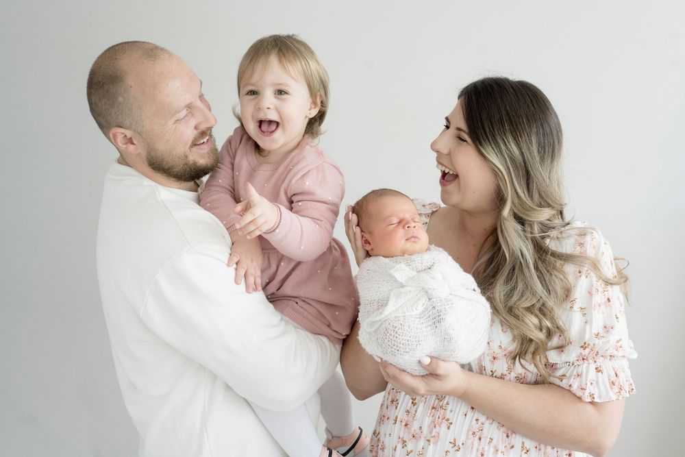 Joyful family moment captured in studio against light grey background.