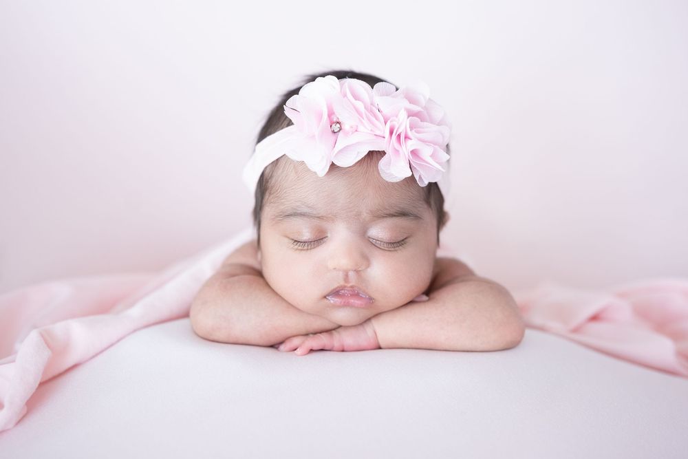 Dreamy pink newborn photography session with soft lighting and floral accents.