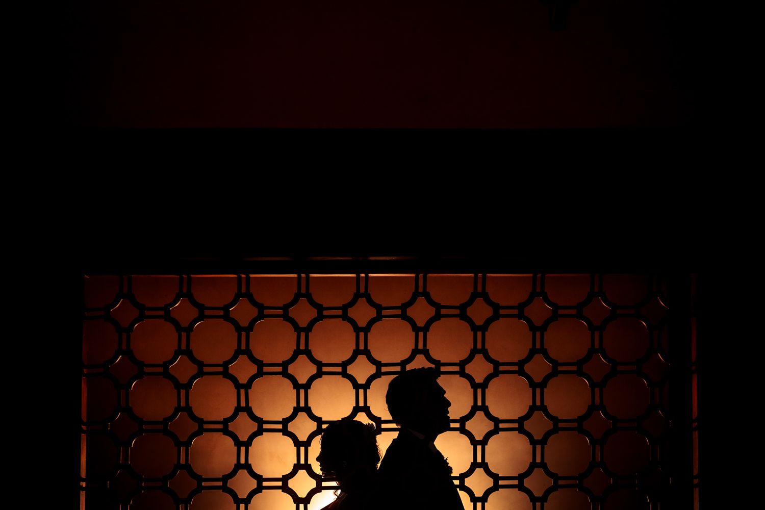 Silhouetted figures against geometric patterns creating dramatic lighting and shadows.