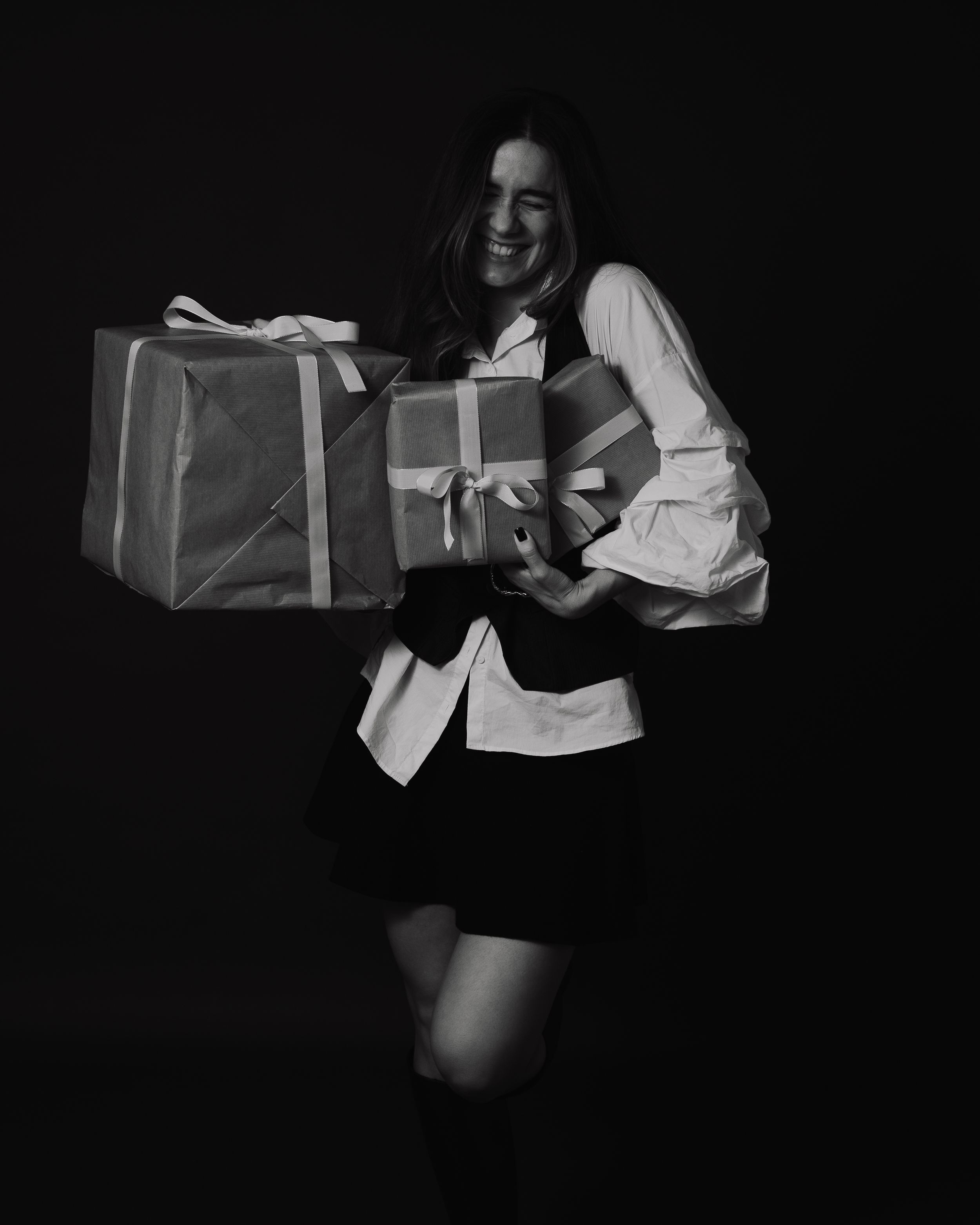 Black and white photo series showing someone in dark clothing opening a gift box against a dark background.