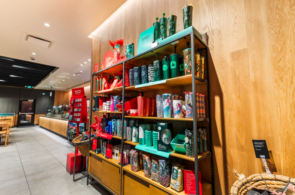 Starbucks retail shelving unit displaying colorful holiday merchandise, tumblers, and coffee products.