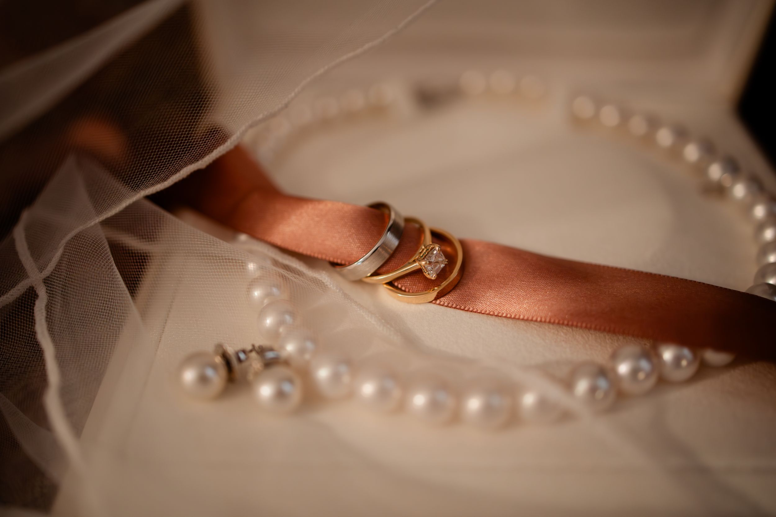 A delicate pearl necklace rests on a soft beige fabric in elegant lighting.