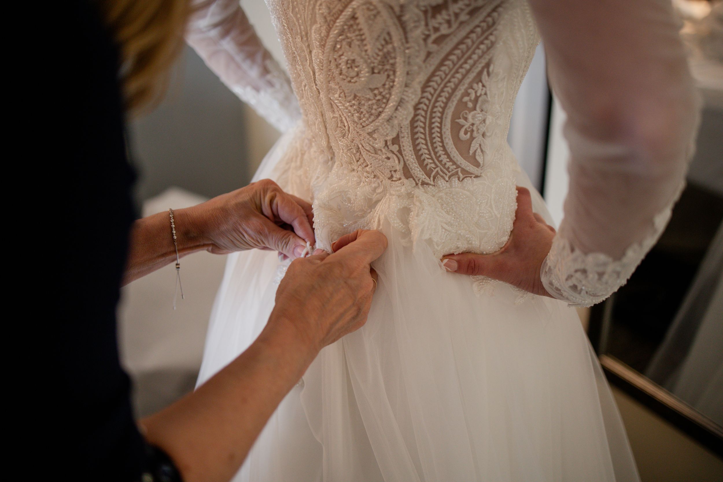 Close-up view of a wedding dress showing intricate lace details and delicate beading along the bodice.