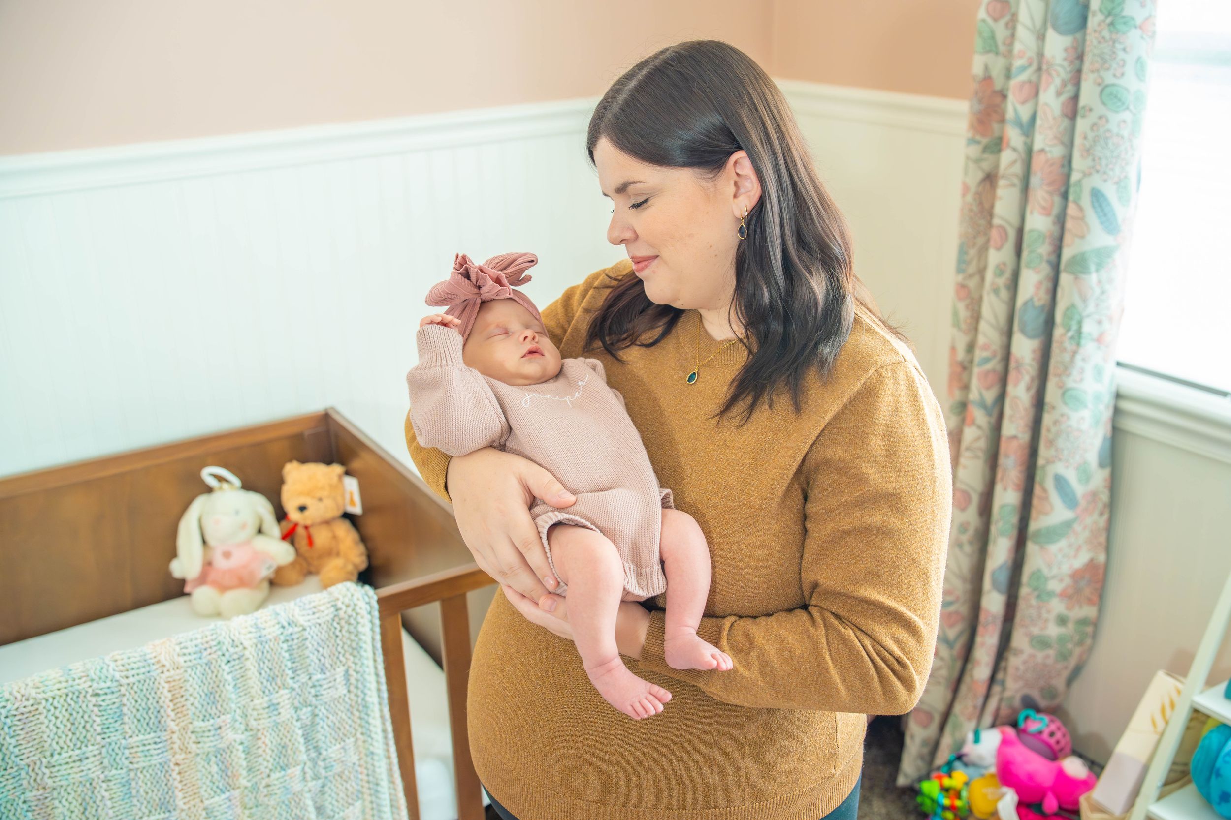 A tender moment of parent-child bonding in a sunlit room with floral curtains and wooden furniture.