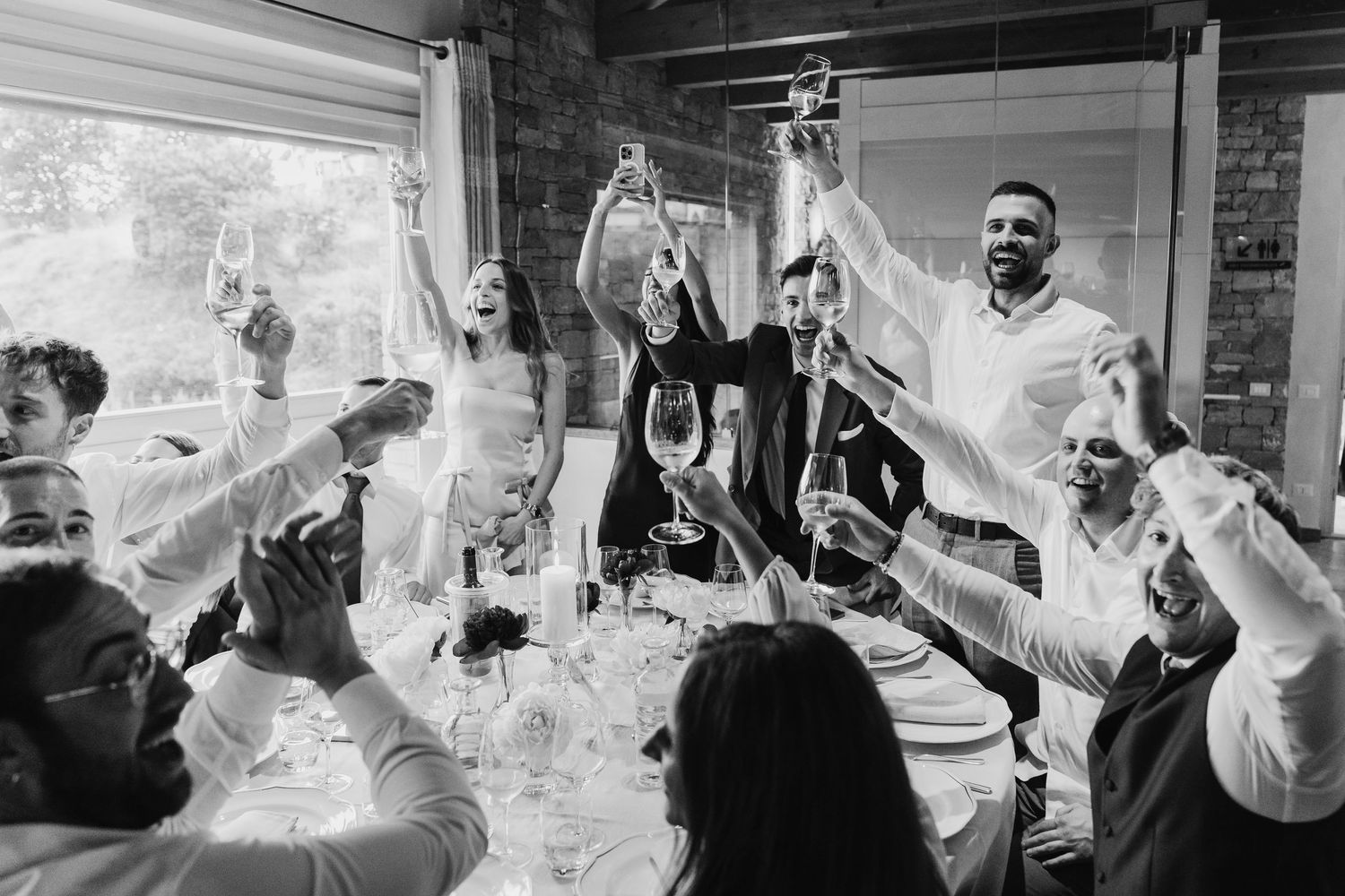 Wedding guests raising glasses in a joyful champagne toast at the reception table.