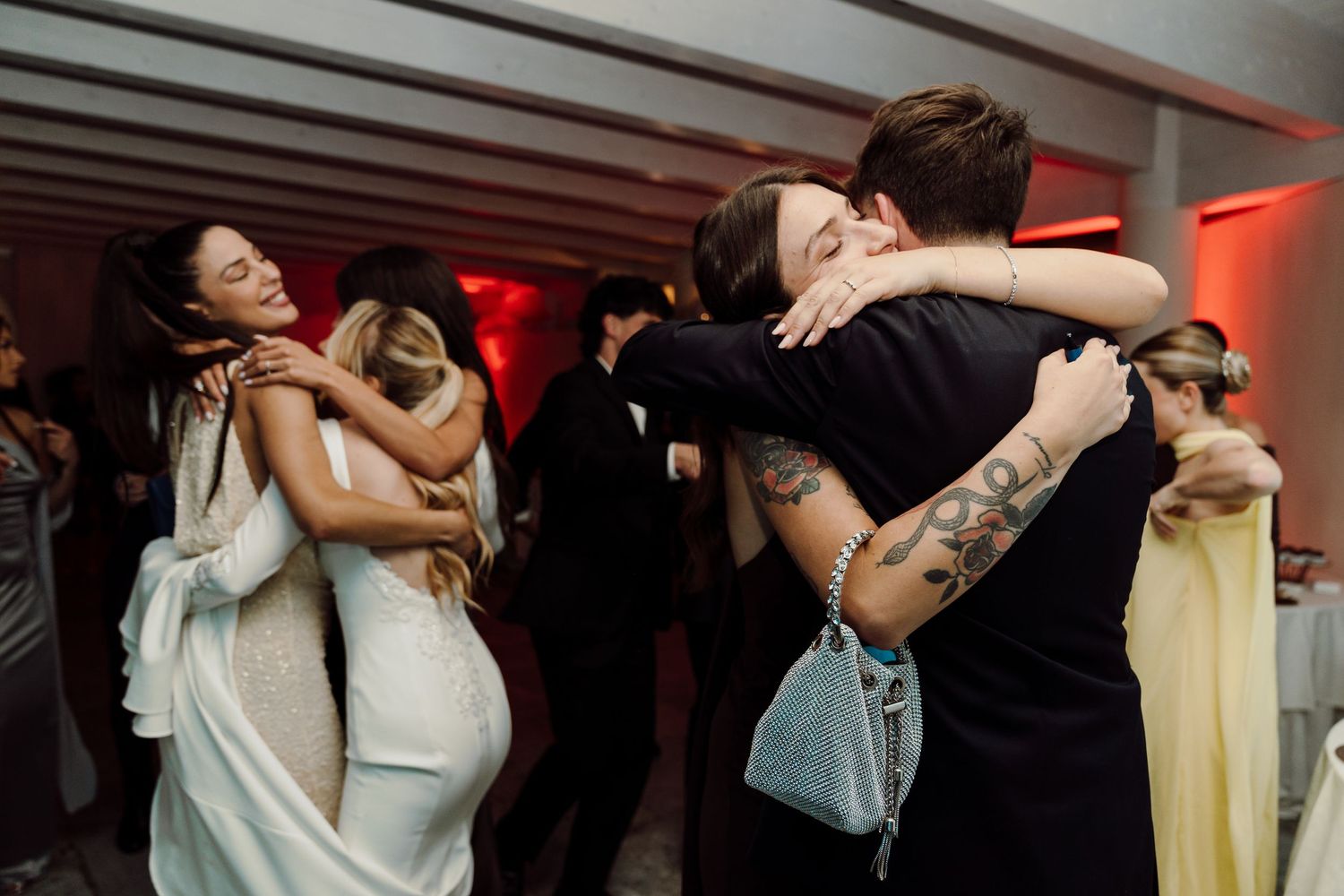 Wedding guests share heartfelt hugs on the dance floor during a reception celebration.
