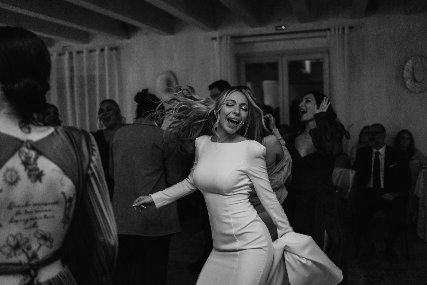 Black and white photo of bride twirling joyfully on the wedding reception dance floor.