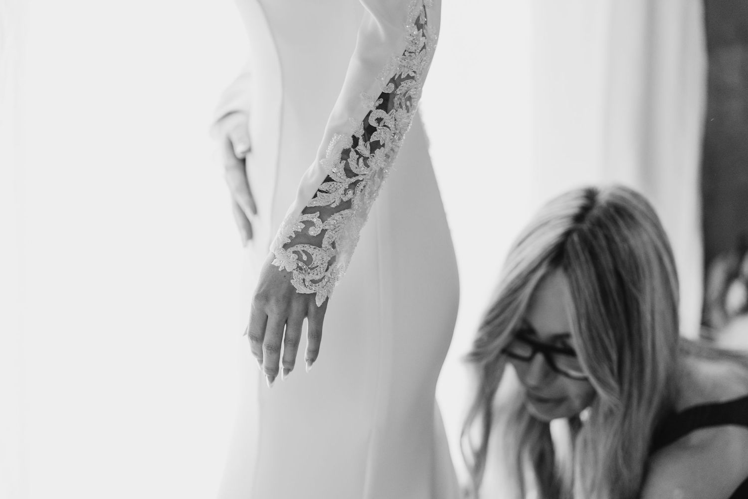 Black and white close-up of intricate lace sleeve detail on a bridal wedding gown.