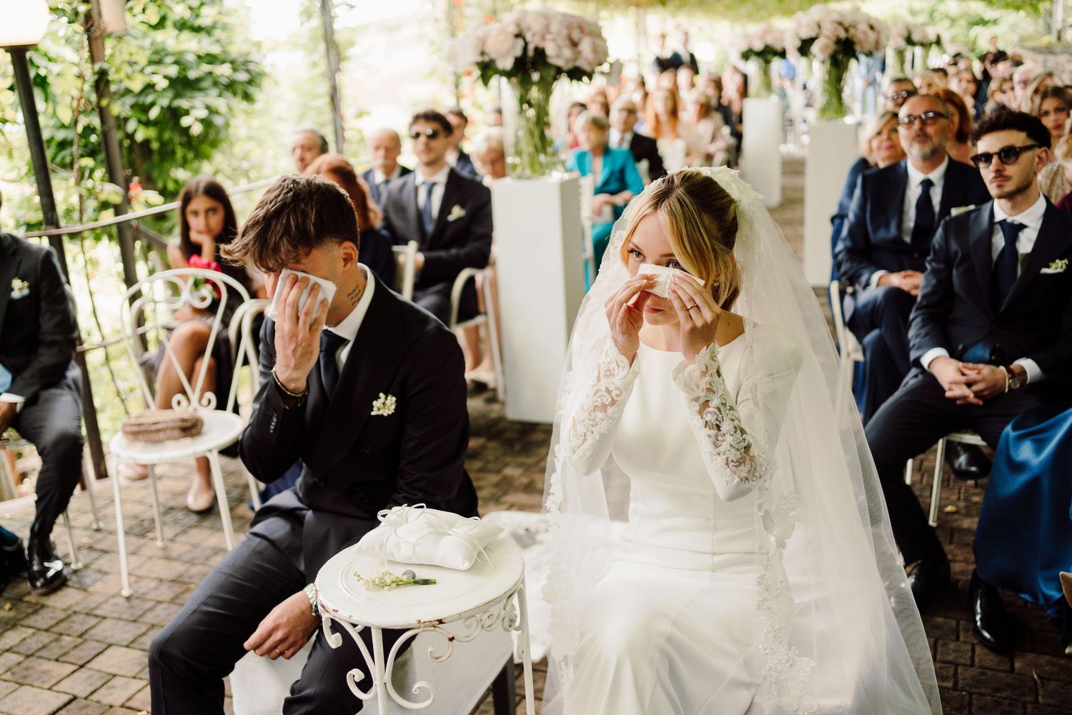 Bride and groom emotionally wiping tears during their outdoor wedding ceremony.