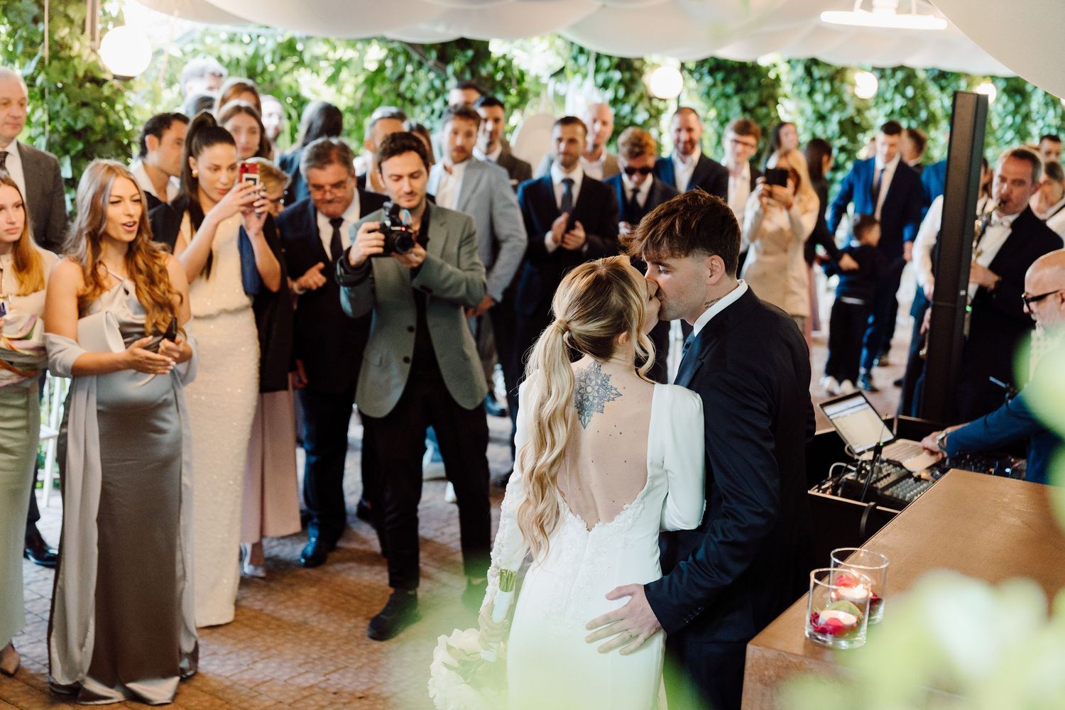 Bride and groom share intimate first dance surrounded by celebrating guests at wedding reception.