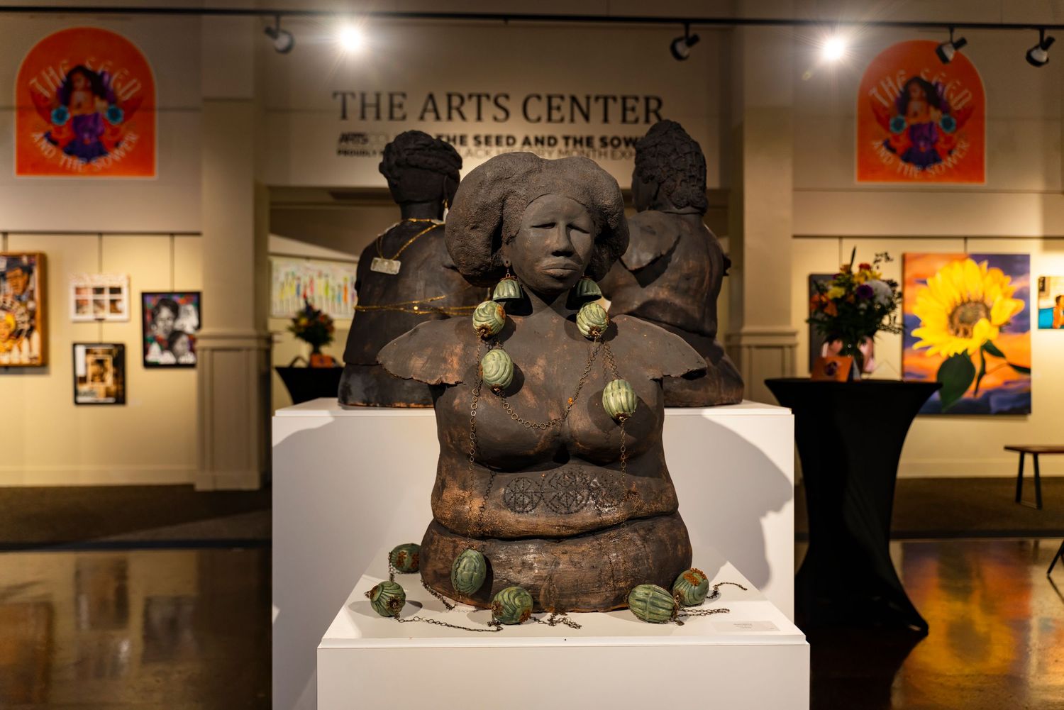 Stone sculpture display at The Arts Center with decorative flags and artwork on walls.