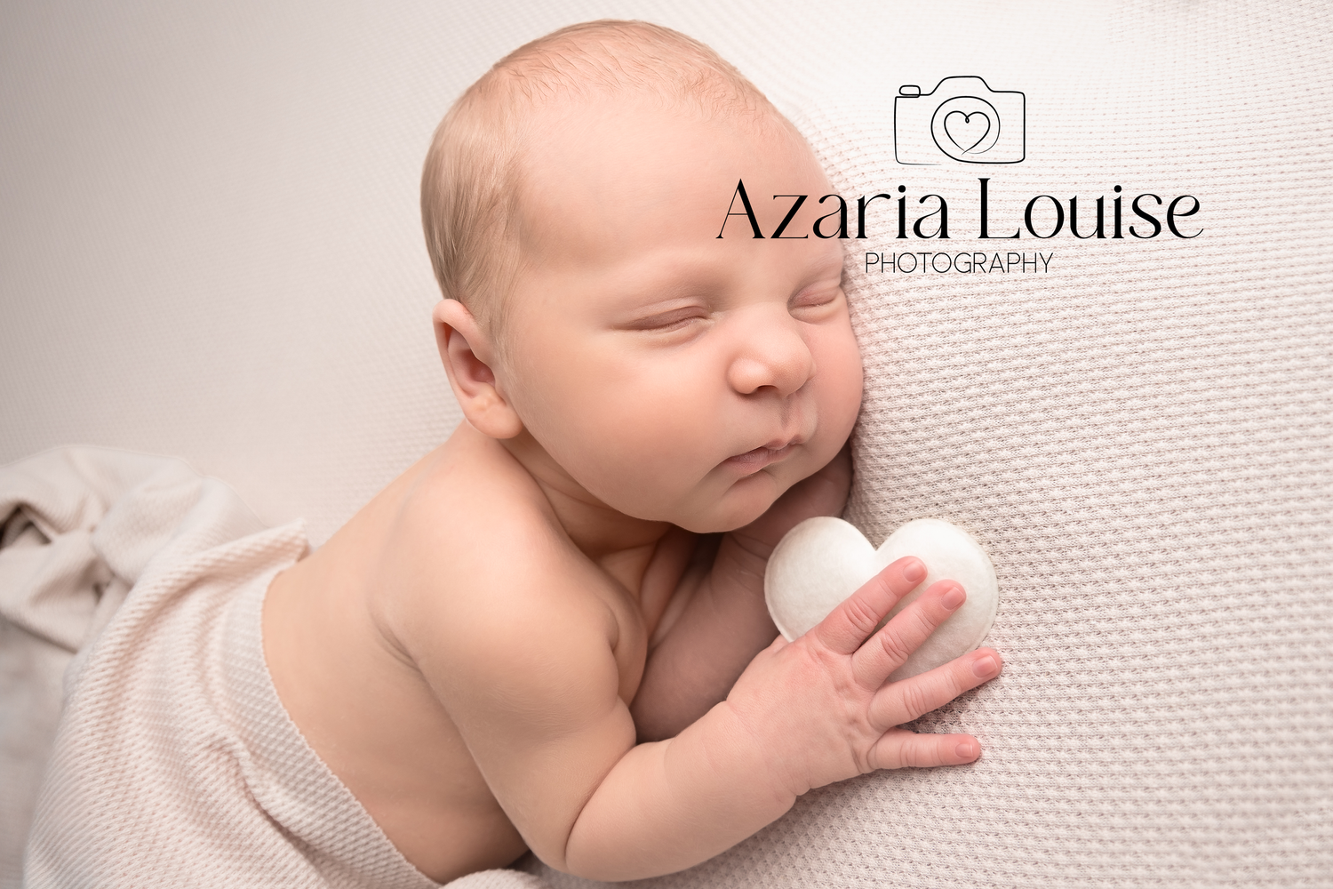 Sleeping newborn baby peacefully rests on textured white fabric during professional photoshoot.
