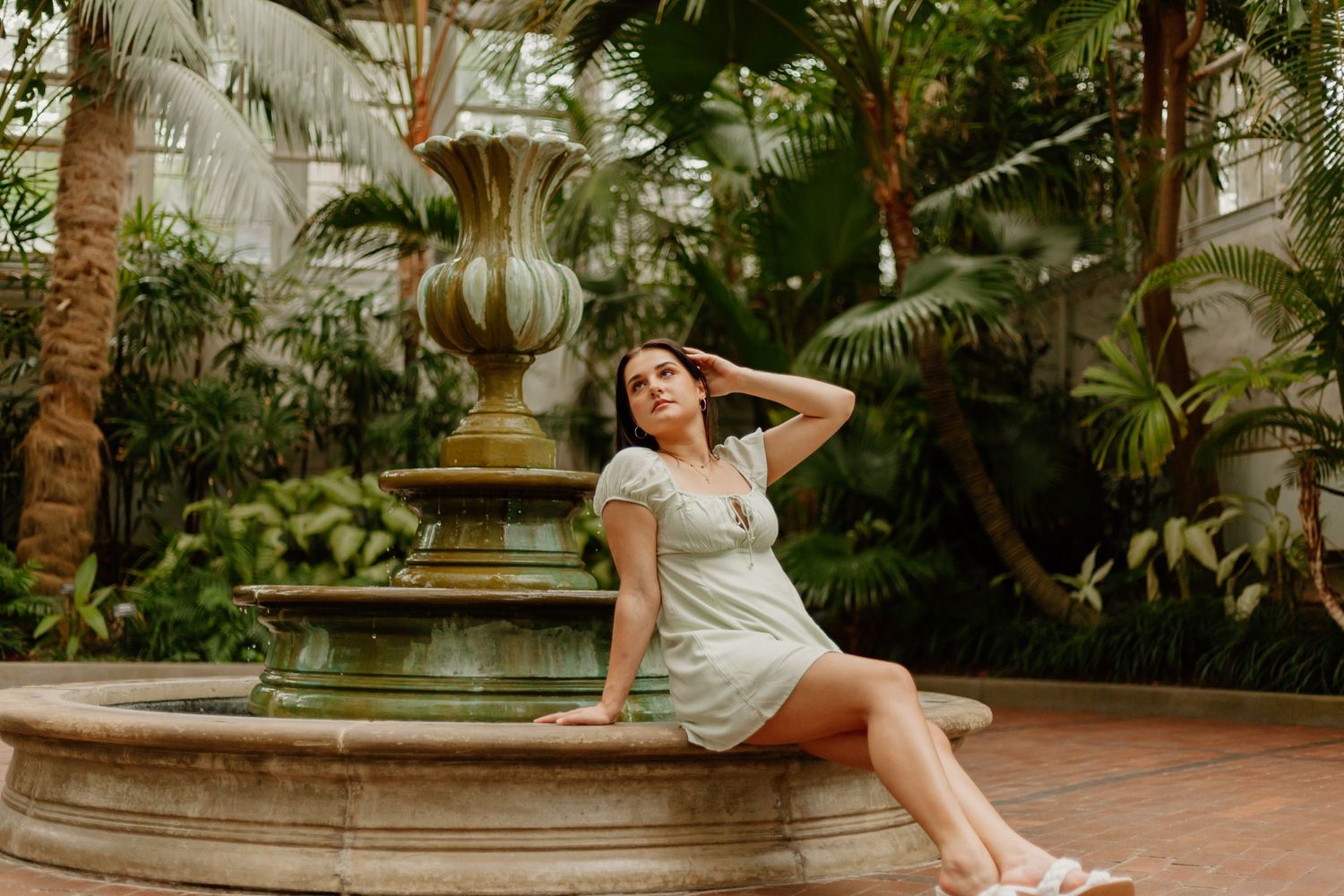 Elegant poses in a lush conservatory with tropical plants and classical architecture.