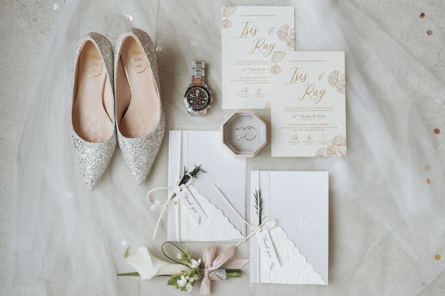 Flat lay of wedding details including sparkly shoes, invitations, and floral elements.