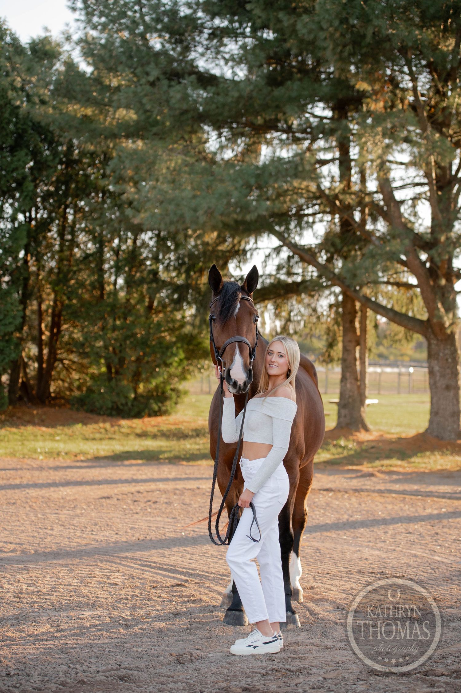 Horse and companion pose together in sunlit wooded setting with pine trees.