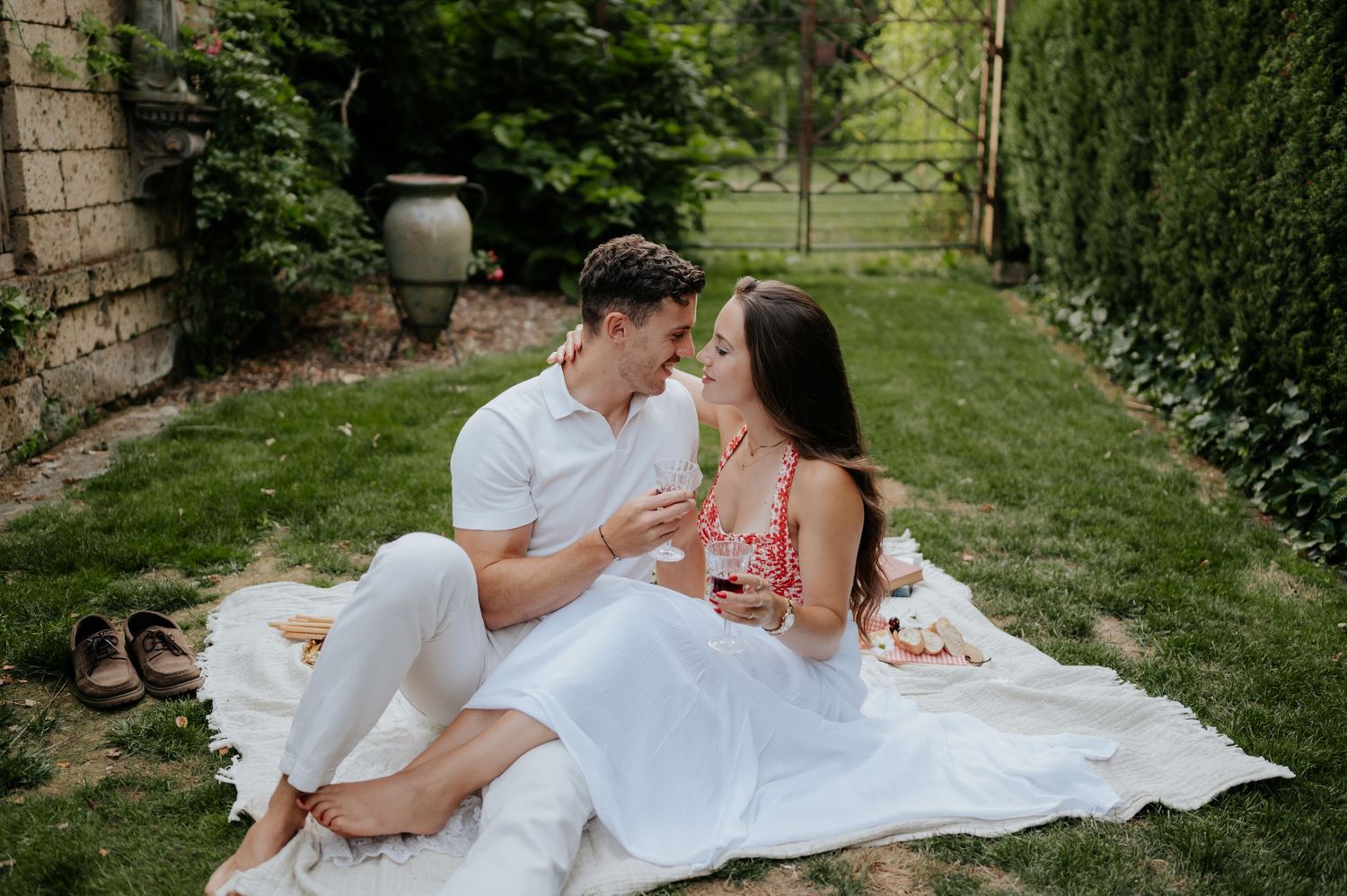 Das Hochzeitspaar posiert in einem üppigen Garten, umgeben von immergrünen Bäumen.