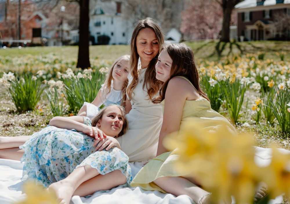 People relaxing on a picnic blanket surrounded by spring flowers in a sunny park.