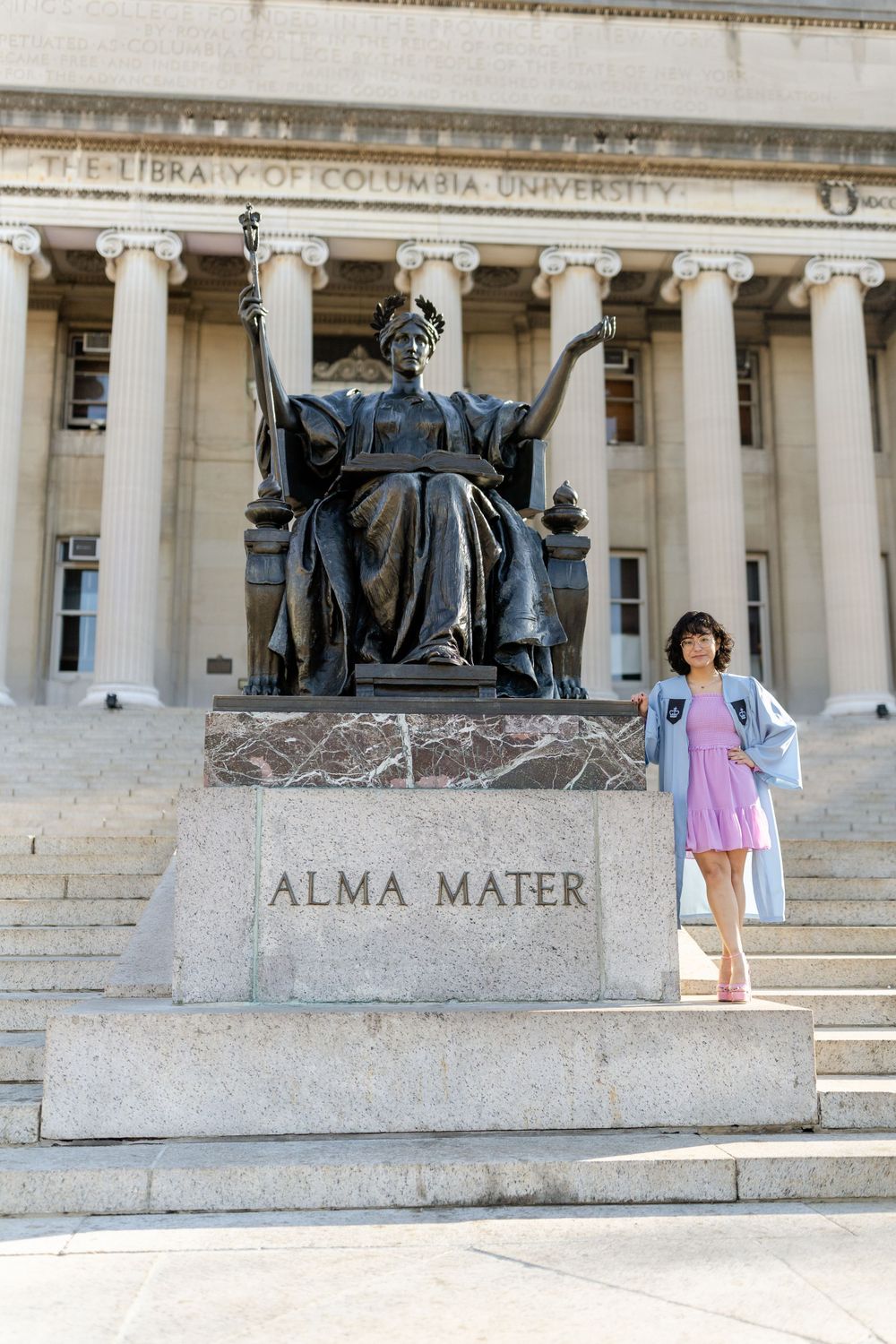 Young graduate stands by Alma Mater statue at Columbia University.