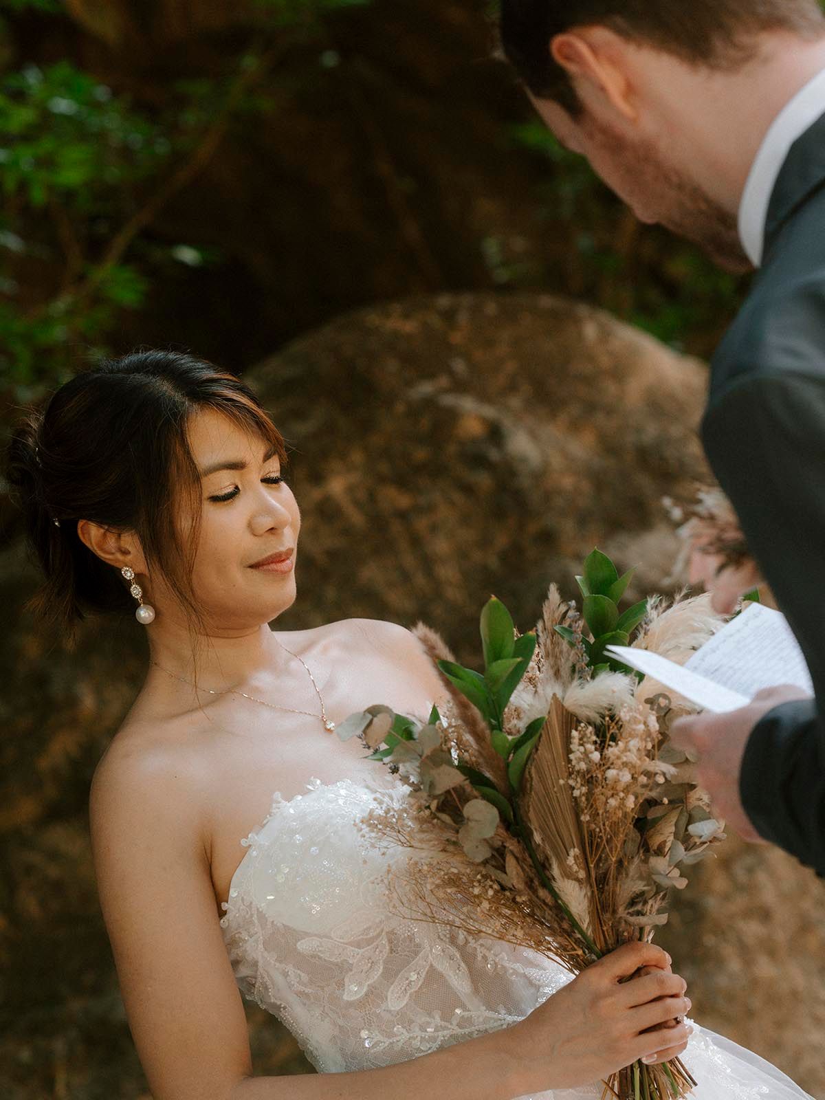 A bride in a white gown holds a dried floral bouquet in Costa Rica.