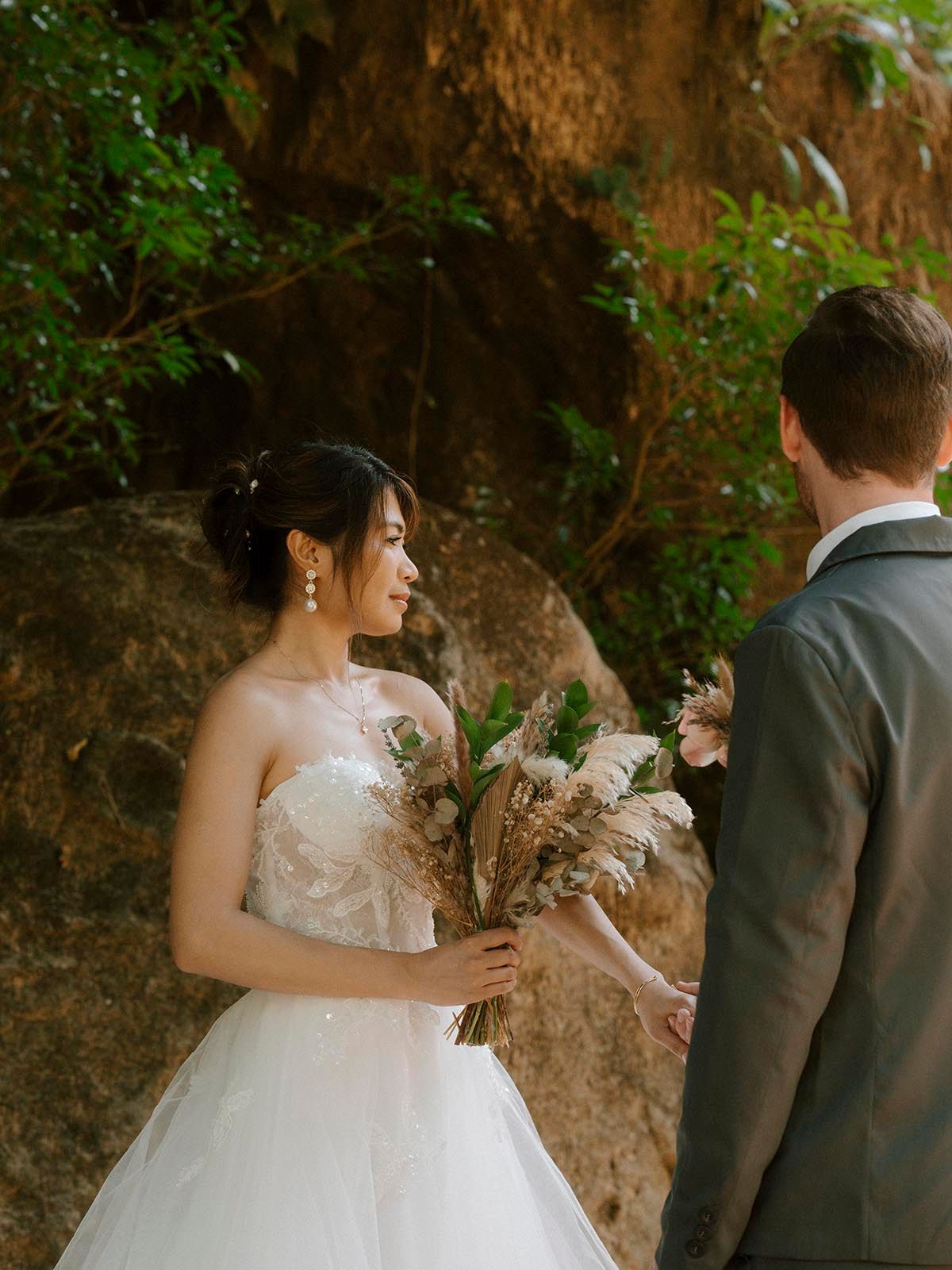 Wedding ceremony taking place near rocky cliffs in natural outdoor setting.