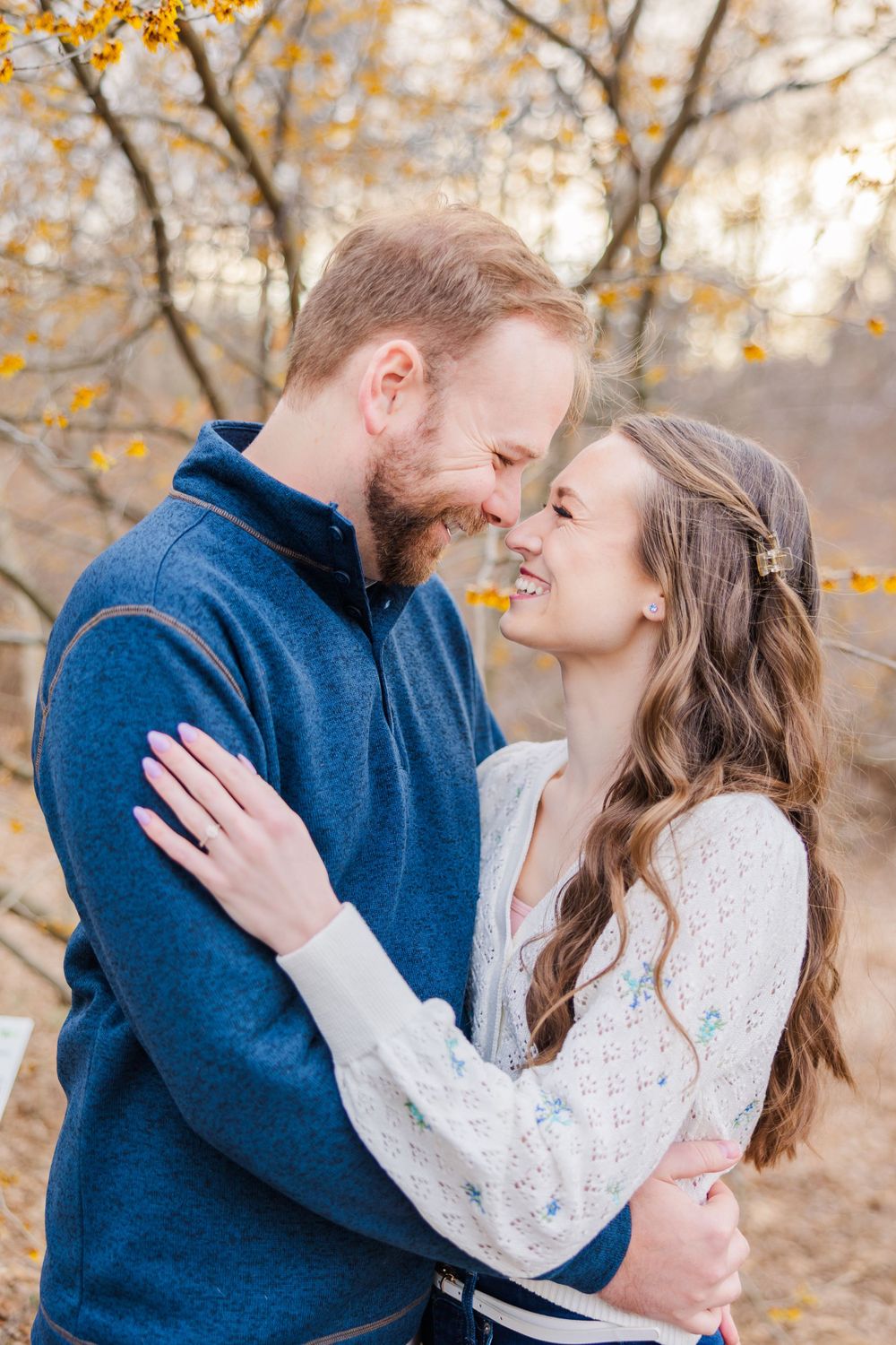 A romantic couple shares an intimate moment among autumn foliage.