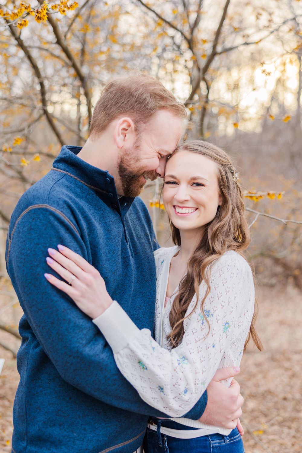 A romantic autumn engagement photo with fallen leaves in the background.
