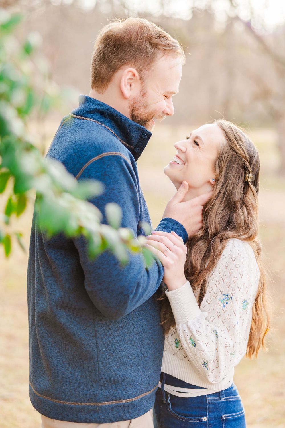 Intimate moment between couple during fall engagement session with soft natural lighting.
