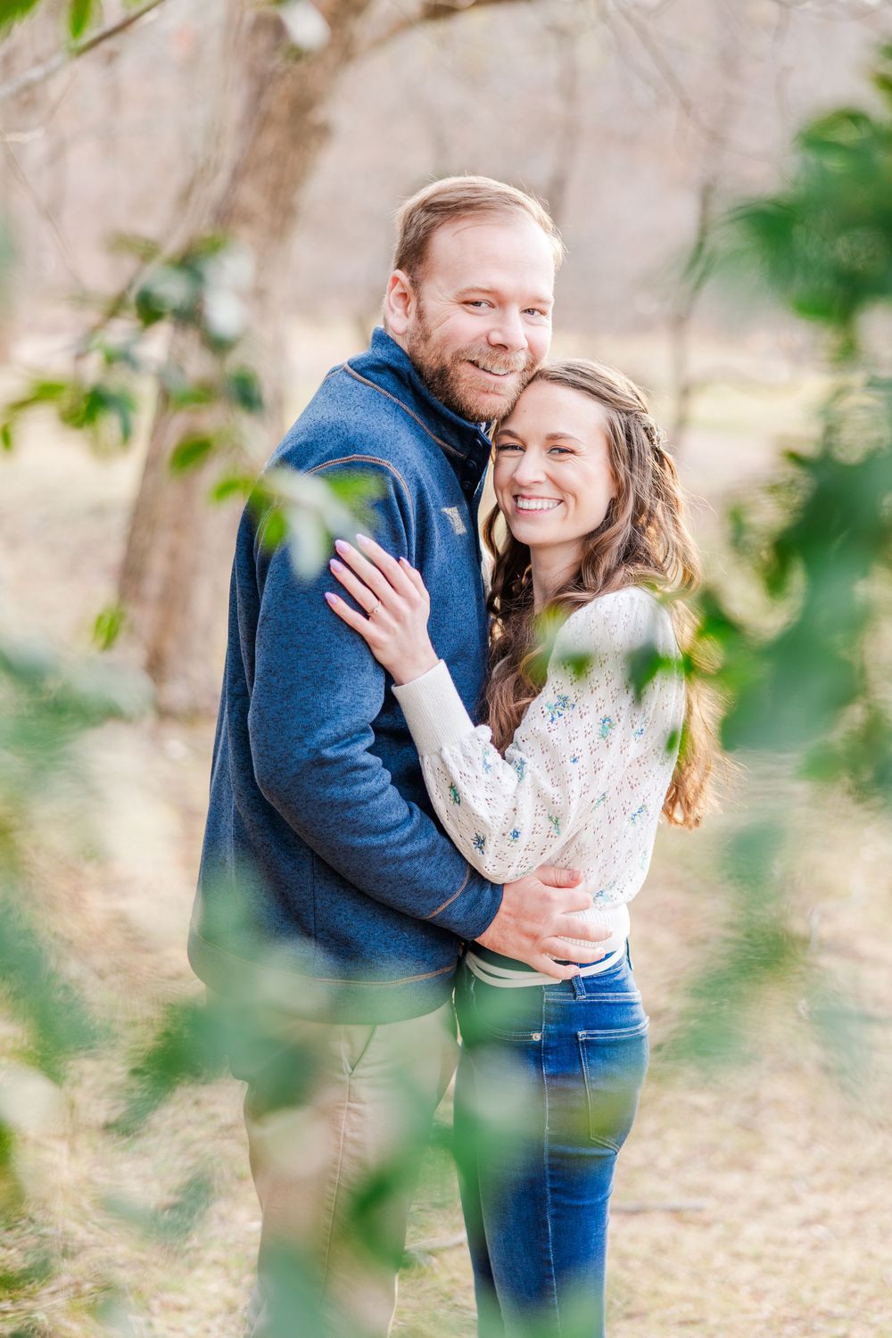 A joyful couple embraces outdoors while wearing blue and white casual attire in a natural setting.