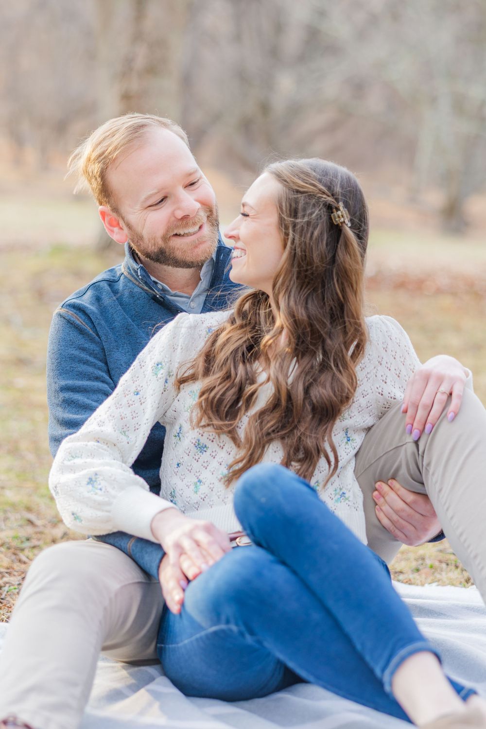 Candid laughing moment captured during autumn engagement session on blanket outdoors.
