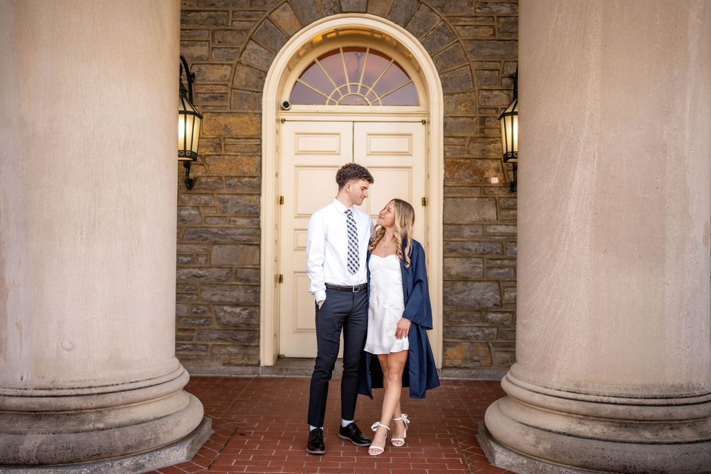 Couple sharing a romantic moment in front of an elegant arched door with stone columns.