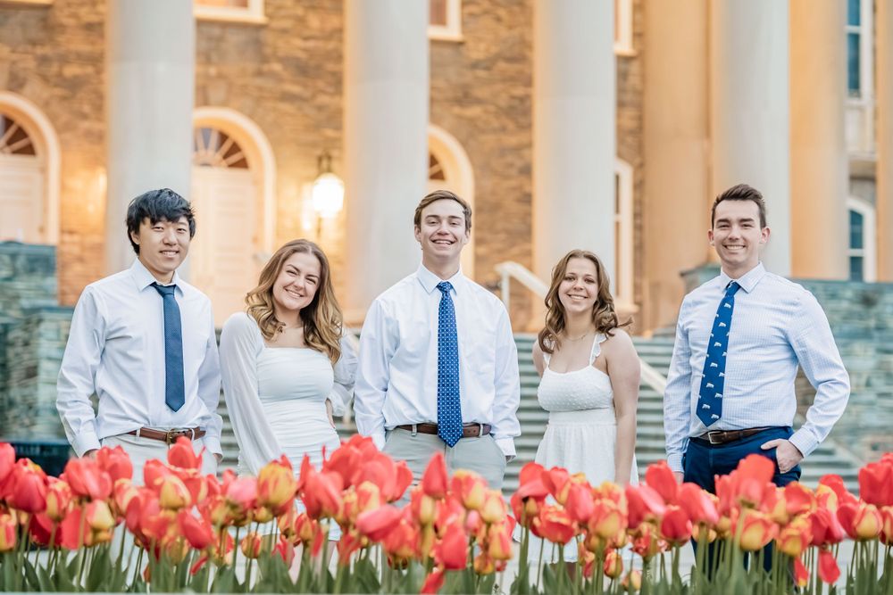 Vibrant orange tulips bloom in front of a stone building with elegant white columns and arched windows.