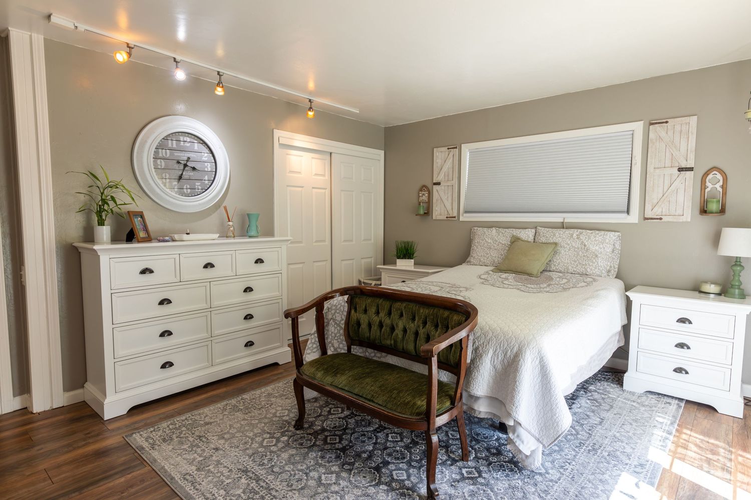 Modern farmhouse bedroom with white furniture, brown leather bench and decorative mirror.