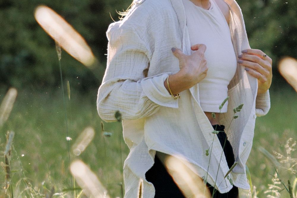 Figure in white sweater moving through tall grass in golden sunlight.