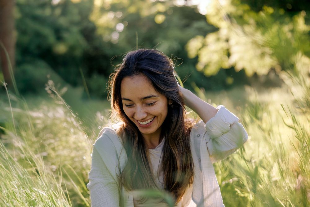 Carefree woman dancing in a sunlit summer meadow wearing white and black.