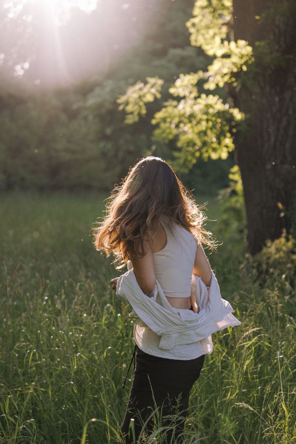 Dancing figure in white clothing moves through a sun-drenched field at golden hour.