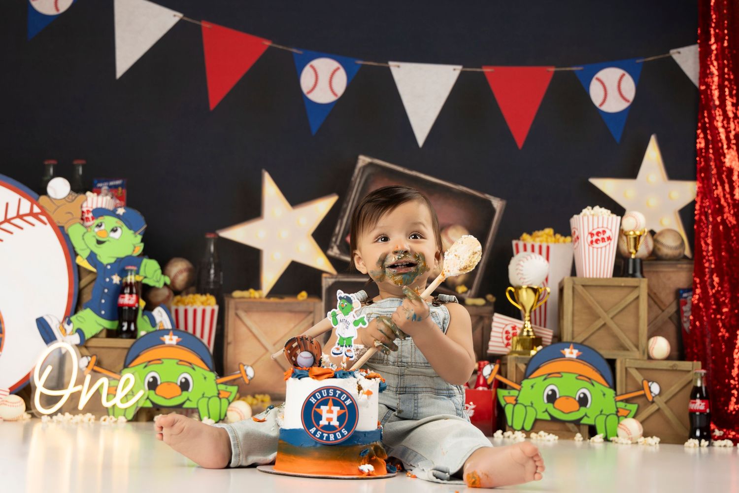 Baseball themed first birthday setup with baby surrounded by sports decor and bunting.