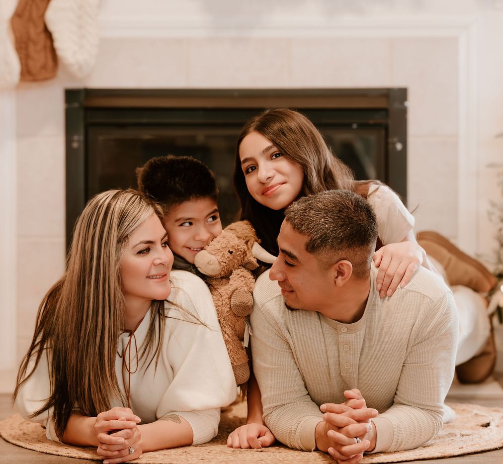 A romantic couple in matching cream sweaters lying on floor during intimate lifestyle photoshoot.