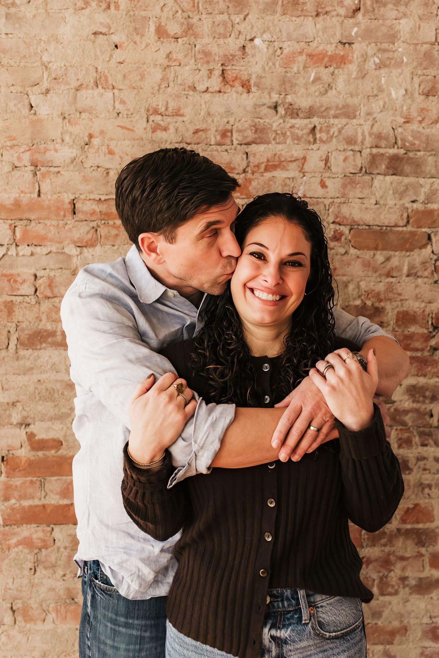 Husband hugs and kisses wife during family photos.