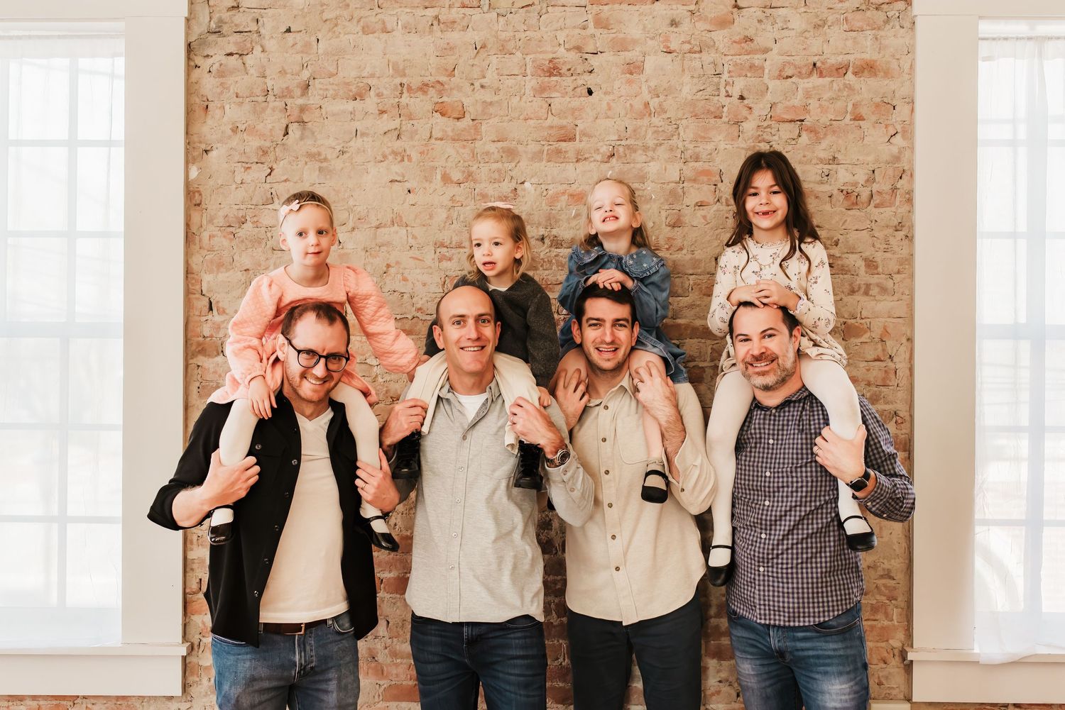 Dads hold daughters on their shoulders and have fun during their extended family photo session at a studio in Cincinnati